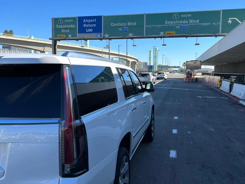 White Cadillac Escalade ESV at the LAX airport return lane with Sepulveda Blvd and Century Blvd signage overhead