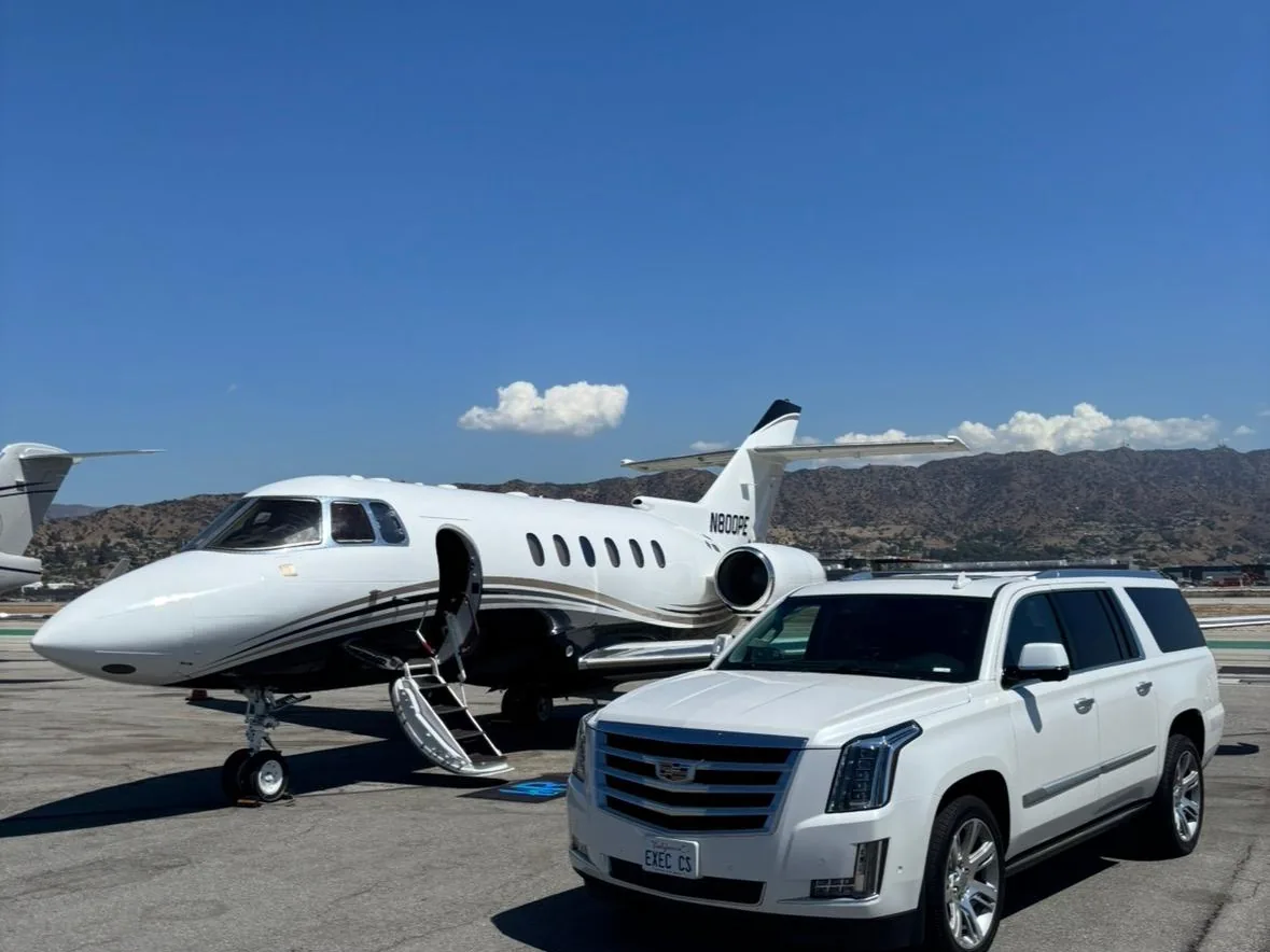 White Cadillac Escalade ESV from Executive Car Service parked beside a private jet on the tarmac, EXEC CS plate visible