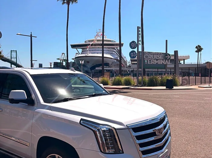 White Cadillac Escalade ESV in front of the Los Angeles Cruise Terminal at San Pedro with a cruise ship behind